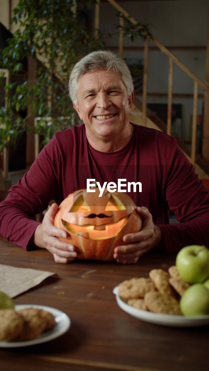 portrait of man with pumpkin on table