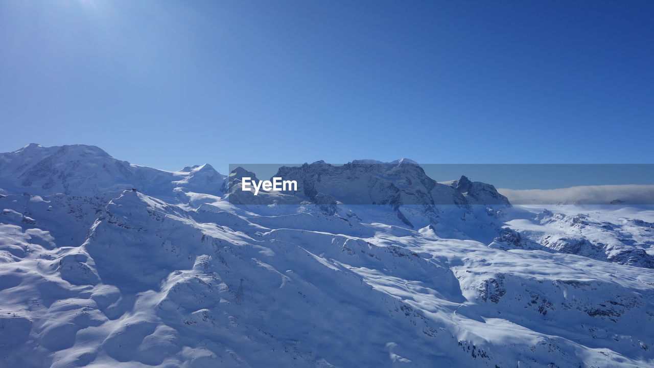 Scenic view of snow mountains against clear blue sky
