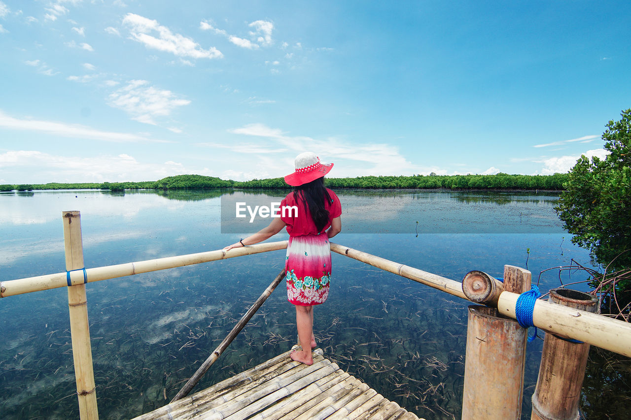 Woman looking at lake against sky