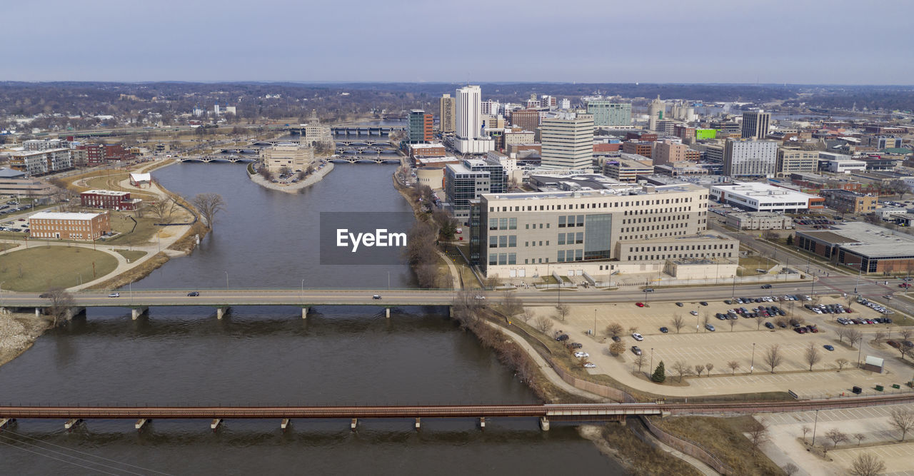 HIGH ANGLE VIEW OF RIVER BY BUILDINGS IN CITY AGAINST SKY