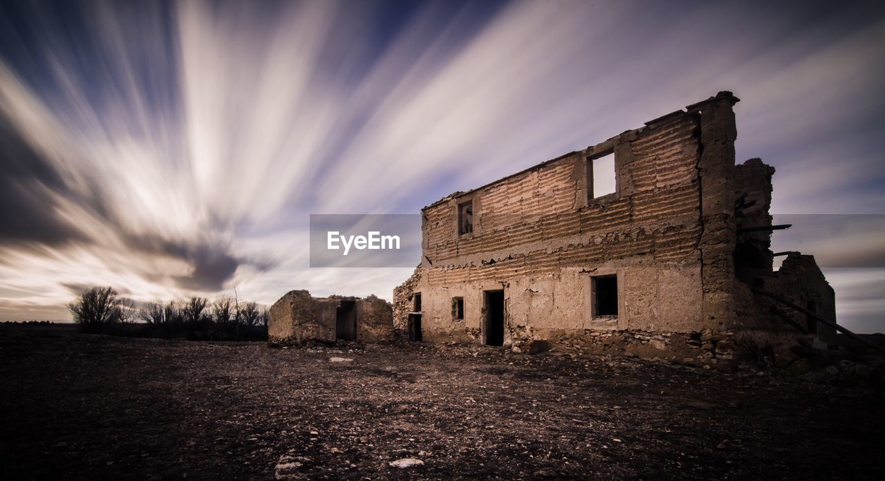 Abandoned and broken building against cloudy sky