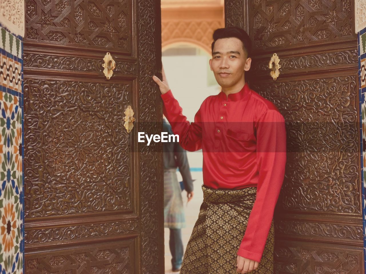 Portrait of smiling man in traditional clothing standing at entrance