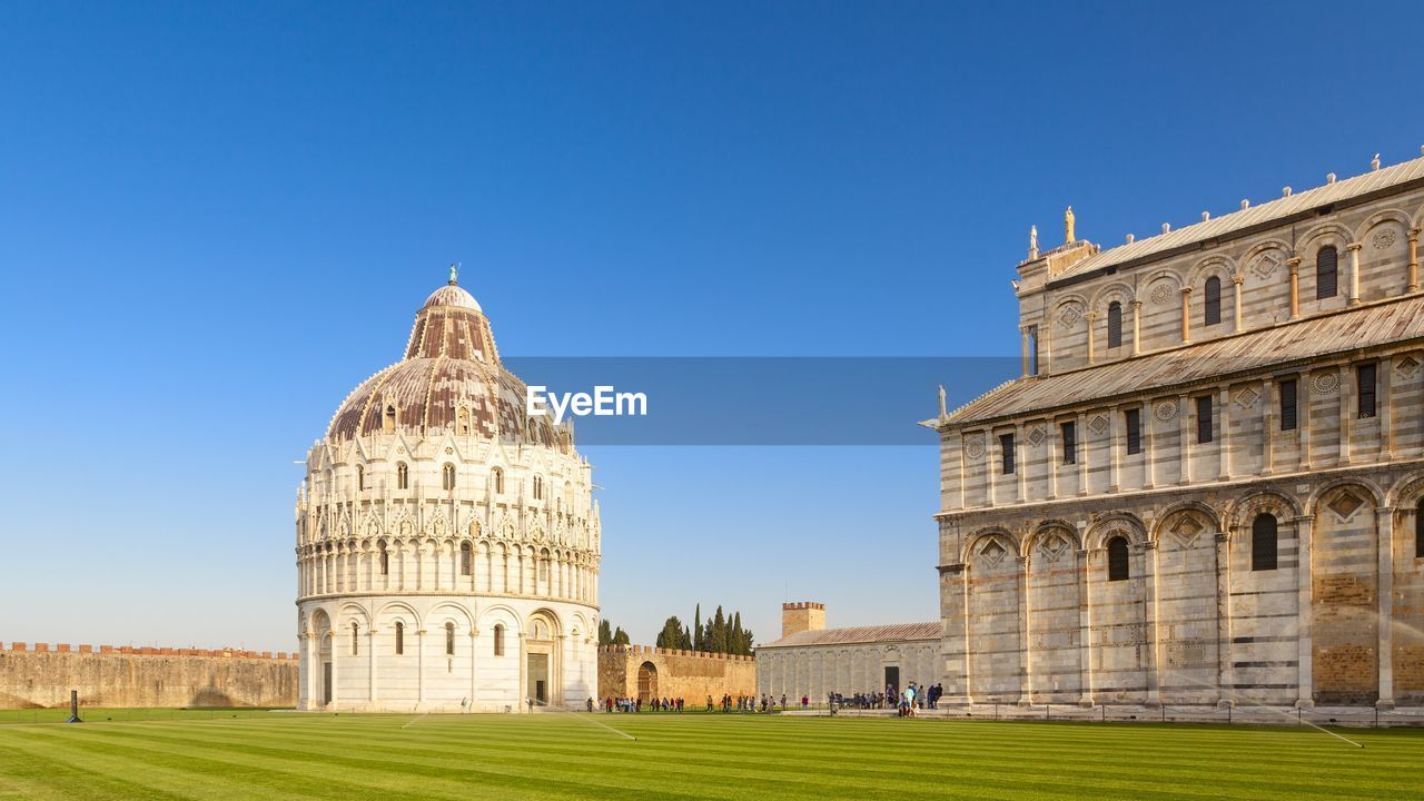 Pisa cathedral and baptistery against clear blue sky