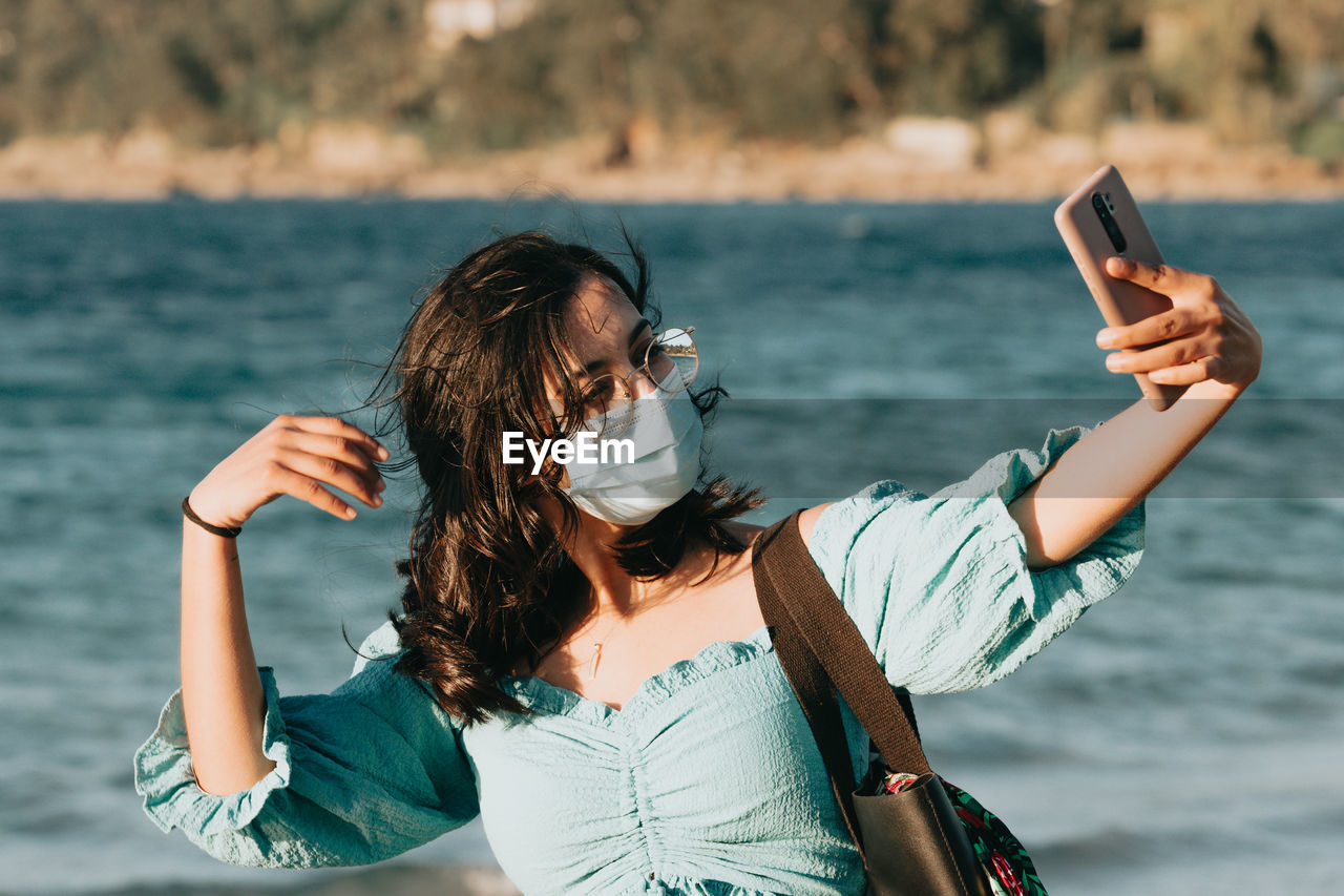 Woman photographing with mobile phone in sea