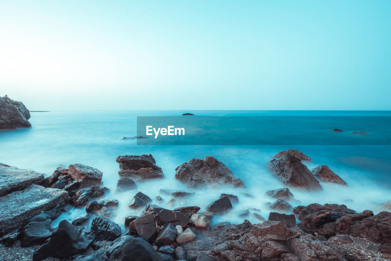 SCENIC VIEW OF ROCKS ON BEACH AGAINST CLEAR SKY