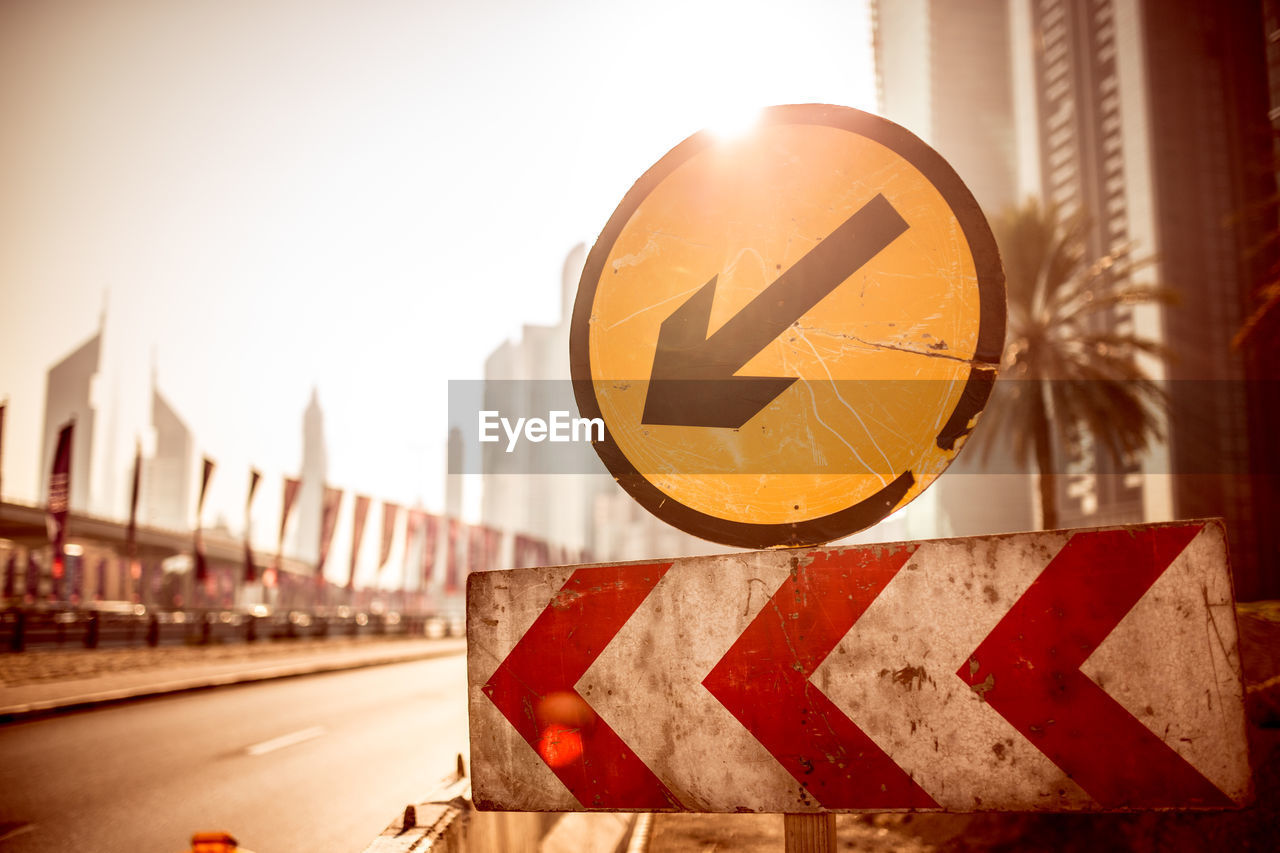 Close-up of road sign against sky in city