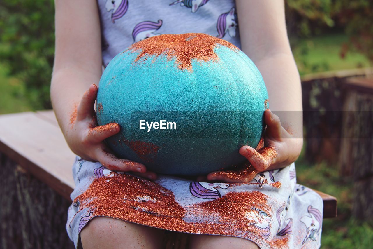 Close-up of girl holding painted pumpkin