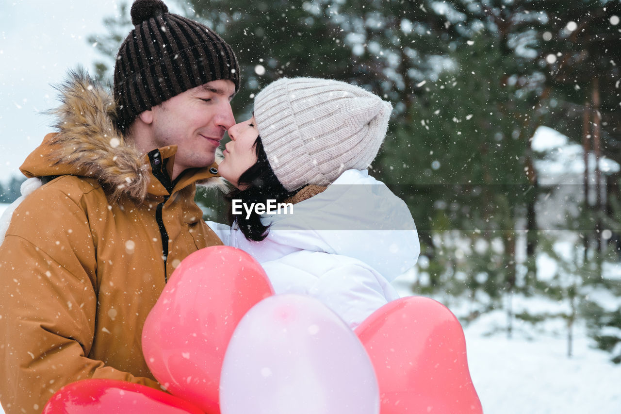 rear view of woman with balloons while standing on snow covered field