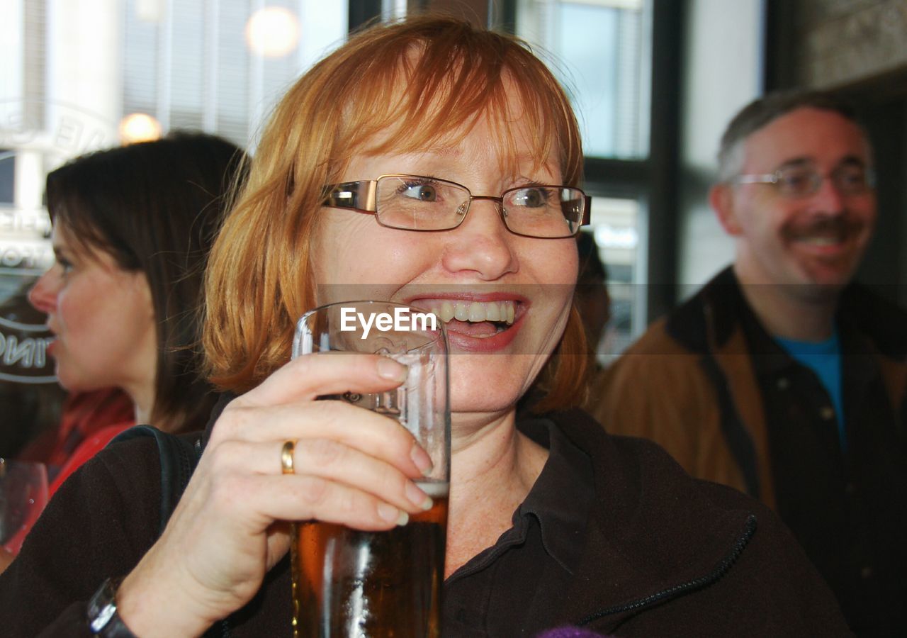 CLOSE-UP PORTRAIT OF A SMILING YOUNG WOMAN WITH DRINKING GLASSES