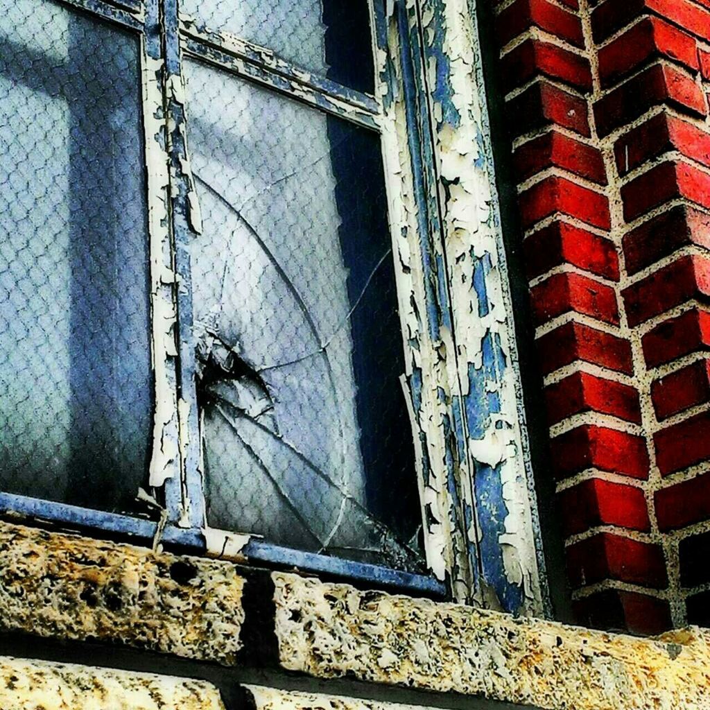 Low angle view of broken glass window of house