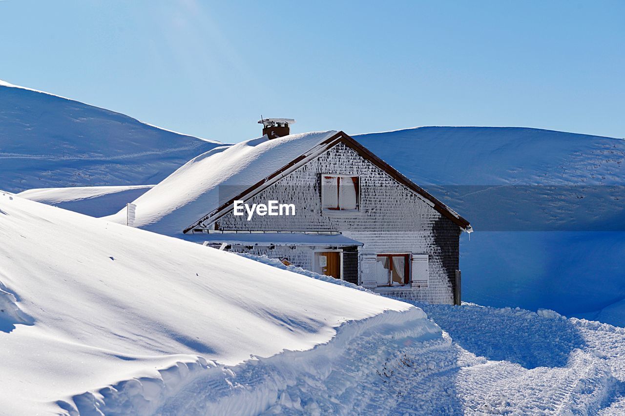 House on snowcapped mountain against sky