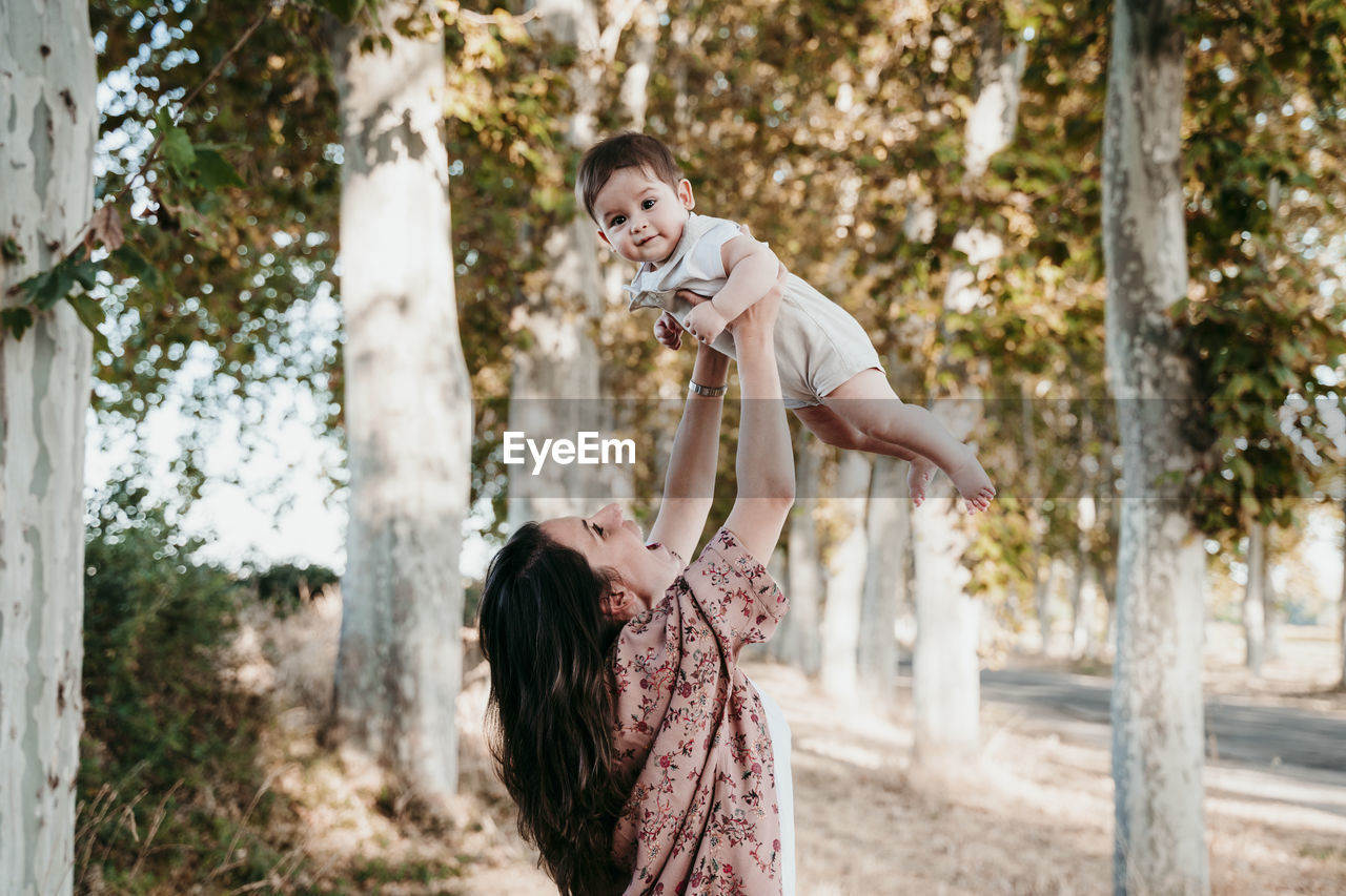 Happy mother playing with baby boy while standing outdoors