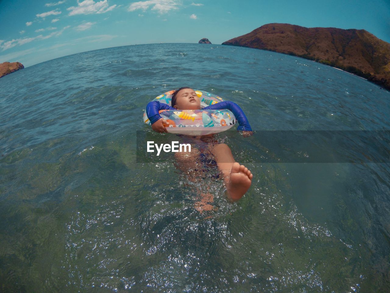 Fish-eye lens of boy swimming with inflatable ring in sea
