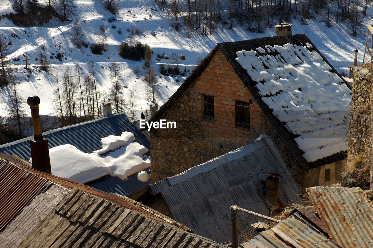 High angle view of houses amidst trees and buildings during winter