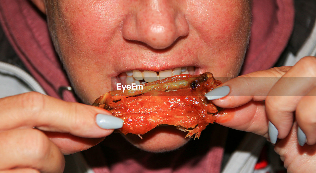 hand, eating, food, food and drink, human mouth, adult, one person, close-up, holding, biting, finger, lip, fast food, men, meat, seafood, human face, skin, nose, women, person, animal, front view, young adult, freshness, lifestyles