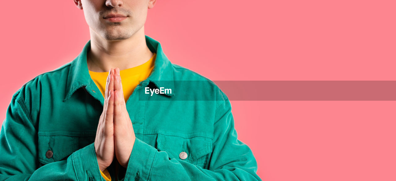 studio shot, one person, colored background, adult, outerwear, portrait, young adult, indoors, copy space, men, front view, hood, sleeve, clothing, green, headshot, emotion, waist up, jacket, blue, person, casual clothing, serious, looking, looking at camera, individuality