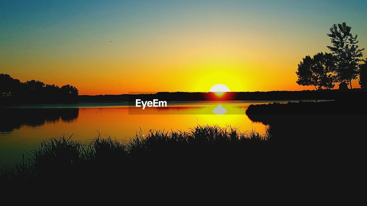 SCENIC VIEW OF LAKE AGAINST SUNSET SKY