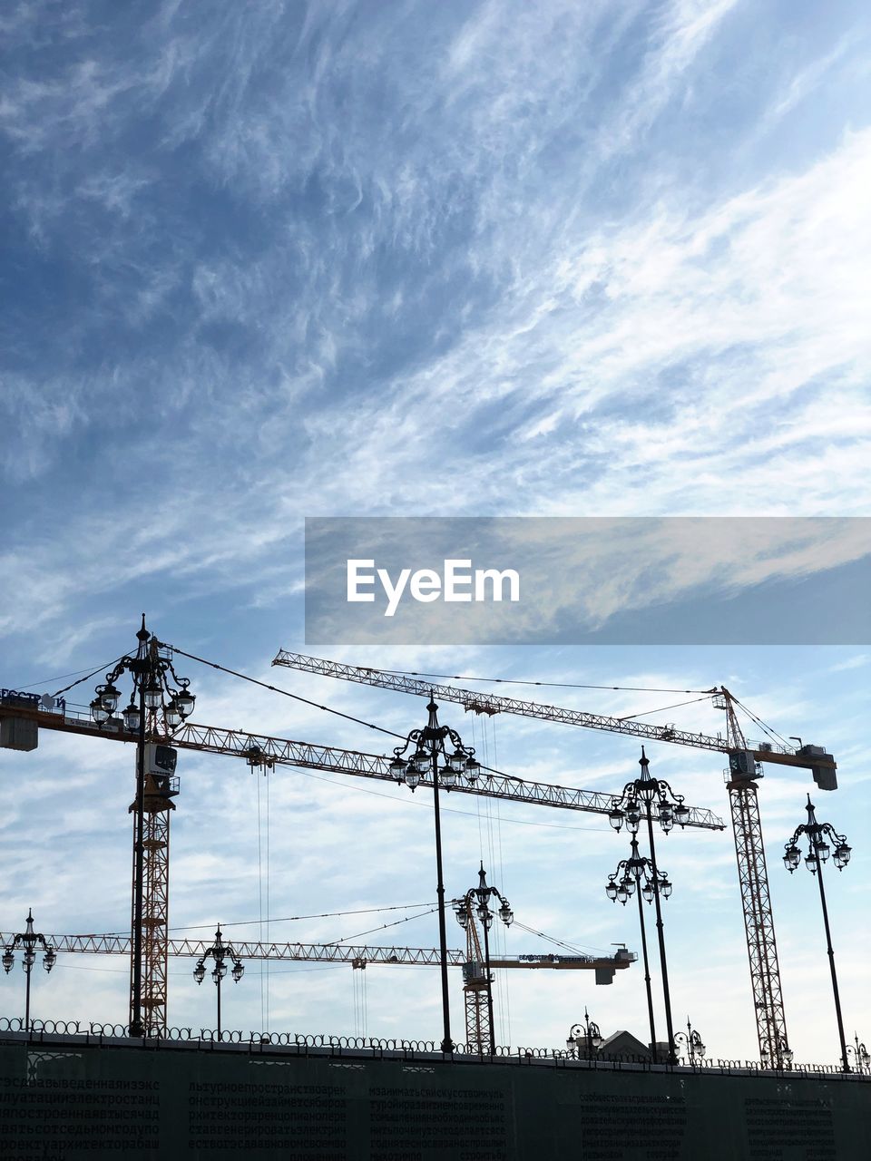 LOW ANGLE VIEW OF CRANES AT CONSTRUCTION SITE AGAINST SKY