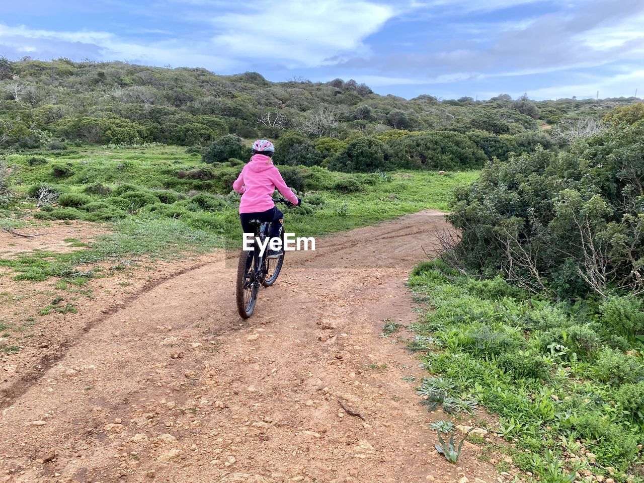 Girl riding a mountain bike along a dirt trail