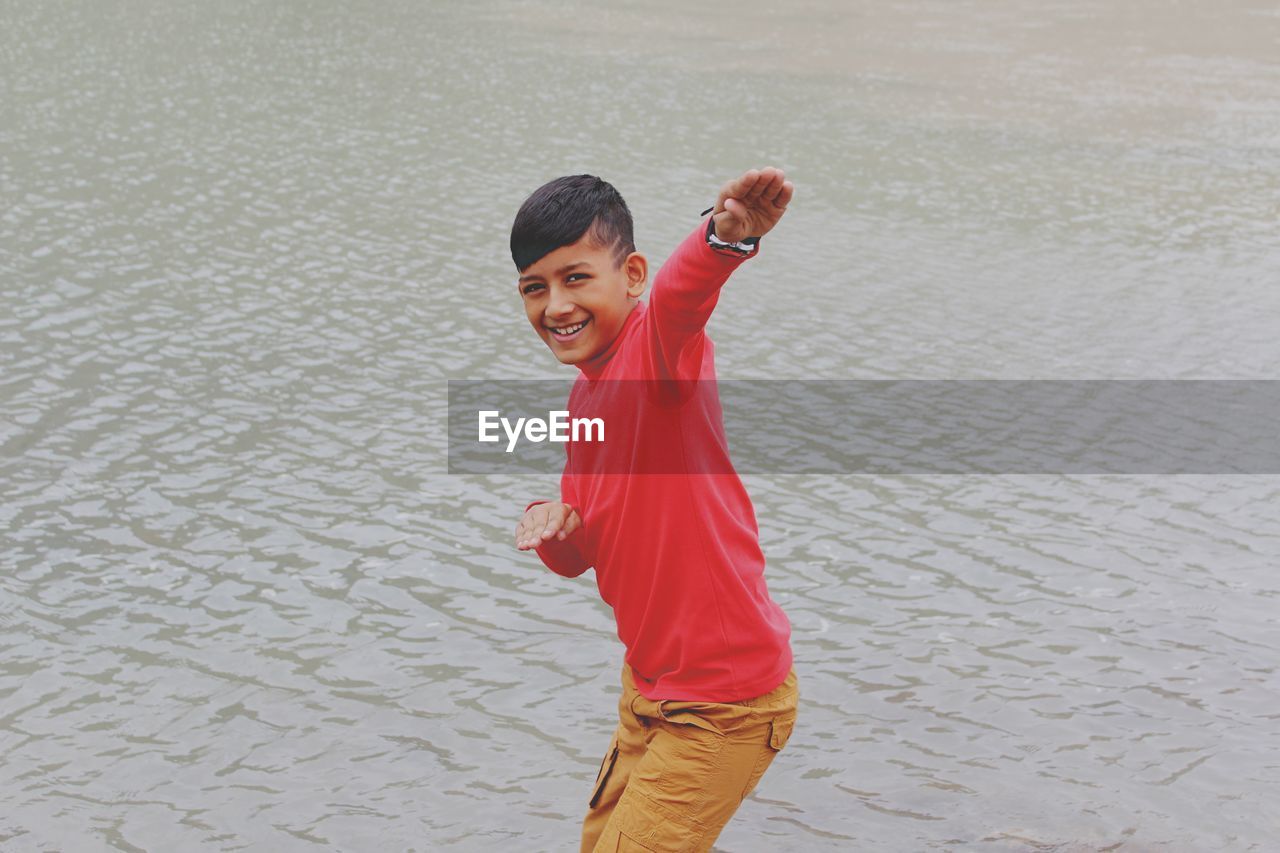 Portrait of boy gesturing while standing in lake