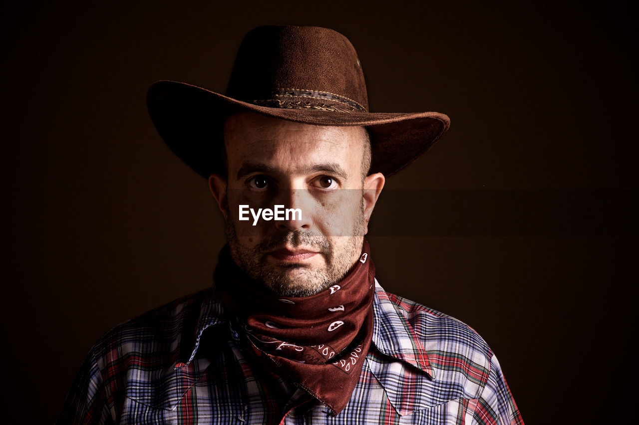 Portrait of man wearing hat against black background