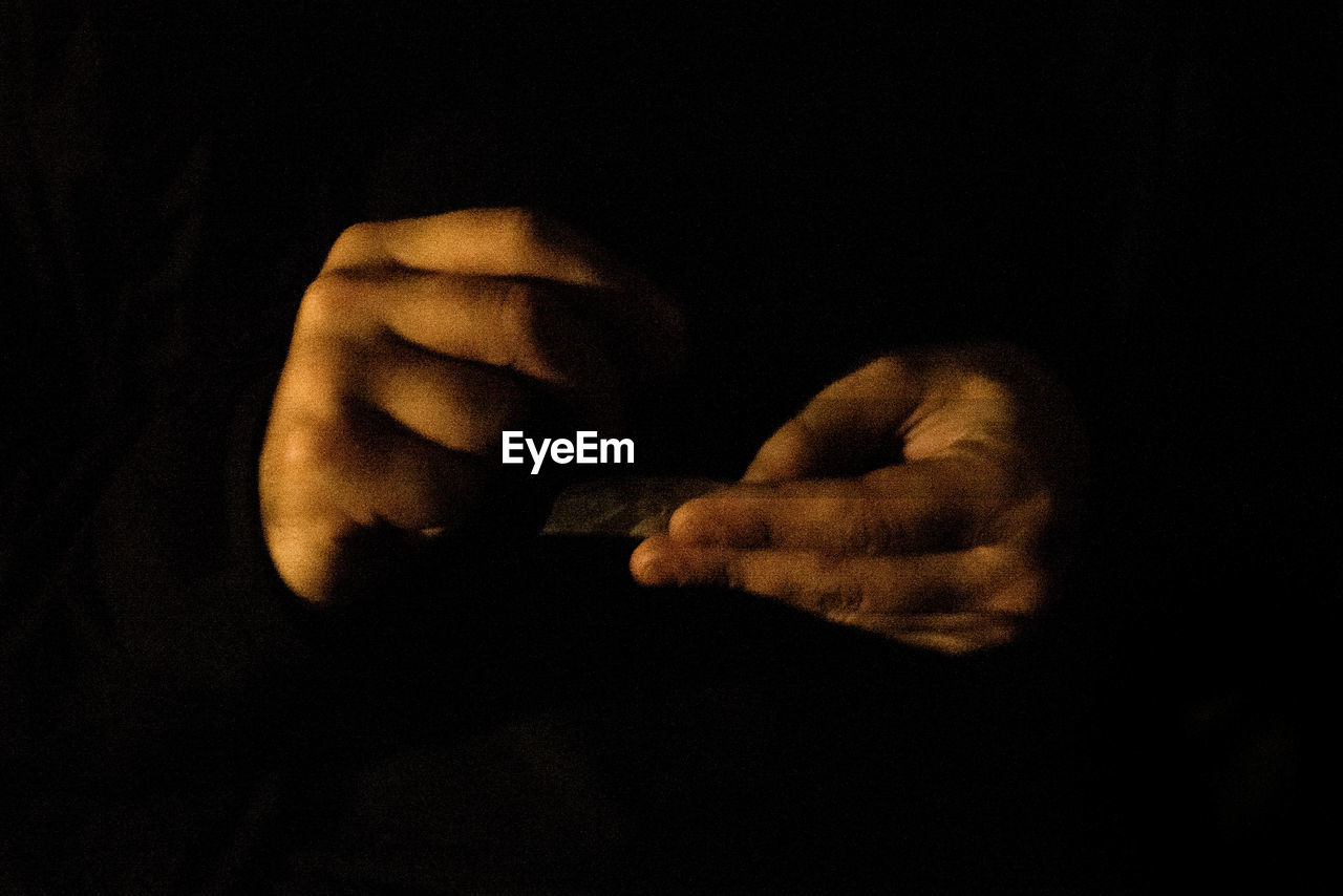 CLOSE-UP OF MAN HAND AGAINST BLACK BACKGROUND