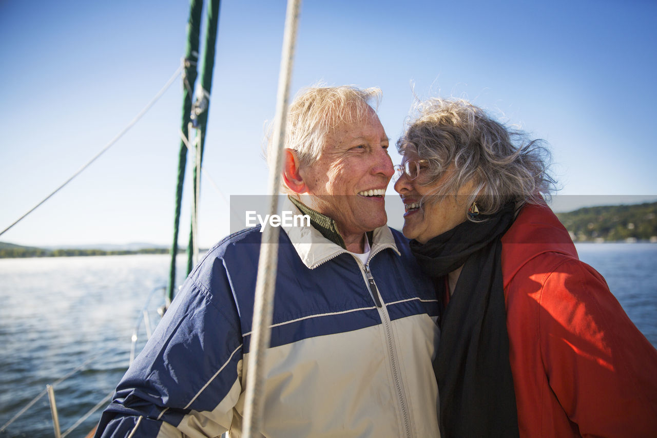 Cheerful senior couple in yacht on sea against clear sky