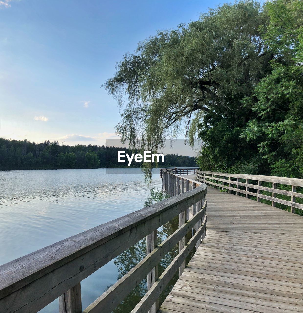 Wooden bridge over lake against sky