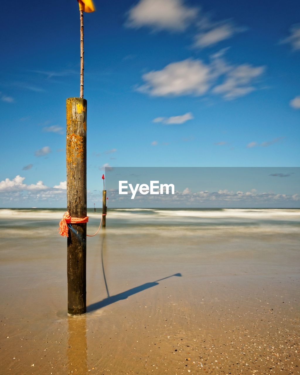 WOODEN POSTS ON BEACH AGAINST SKY