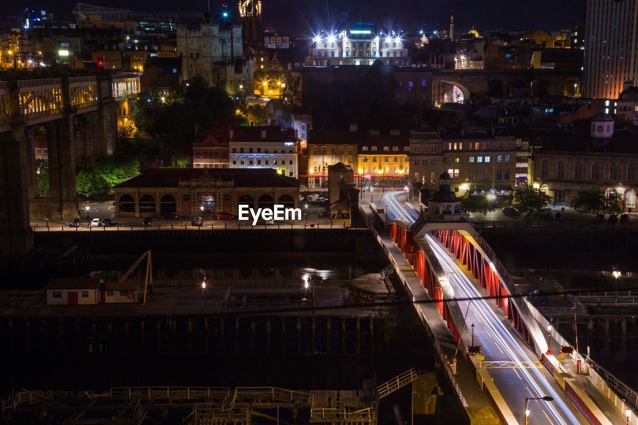 HIGH ANGLE VIEW OF ILLUMINATED CITY AGAINST SKY AT NIGHT