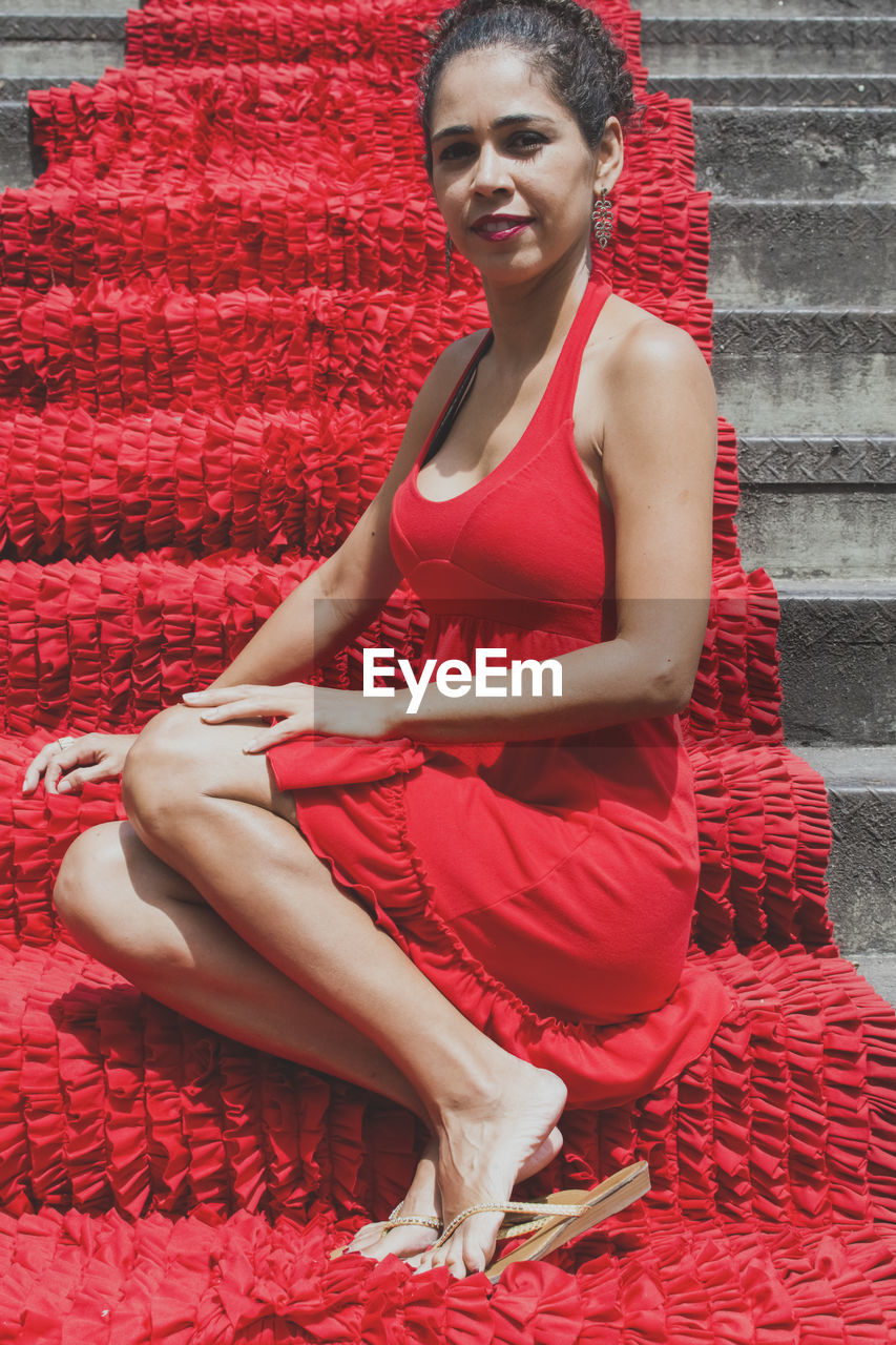 Portrait of a woman sitting on the red stairs. 