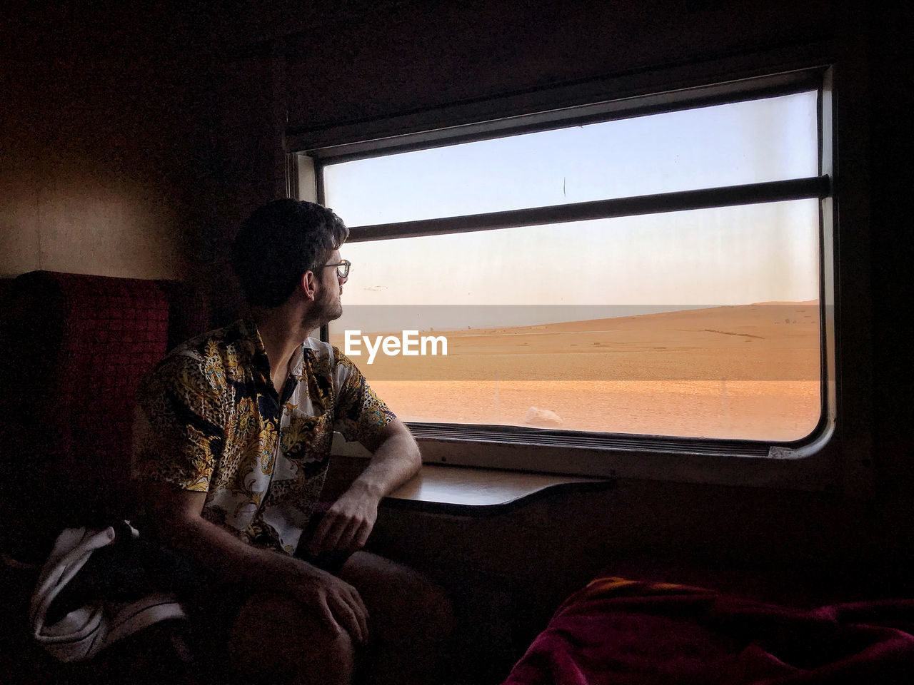 Young man looking through window while sitting in train