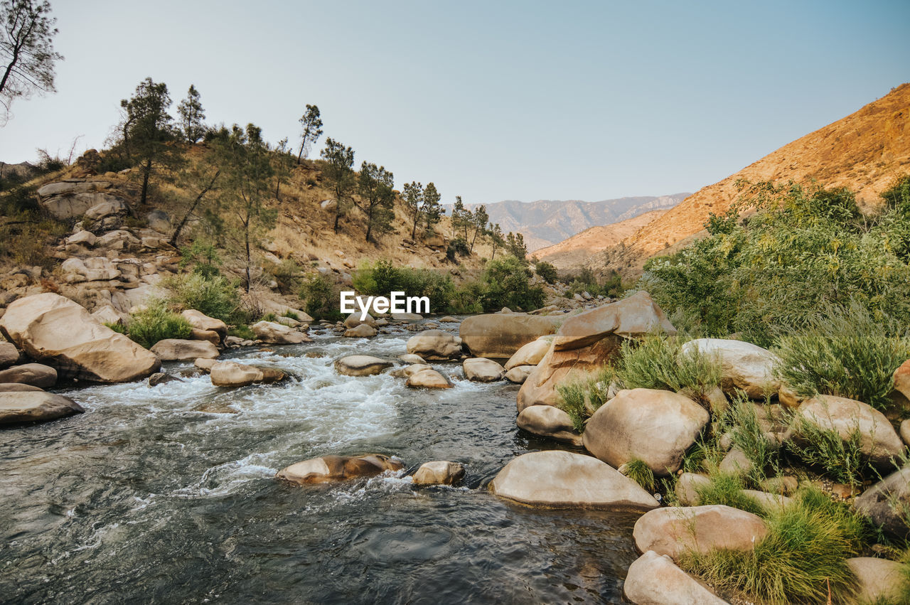 Stream flowing through rocks against sky