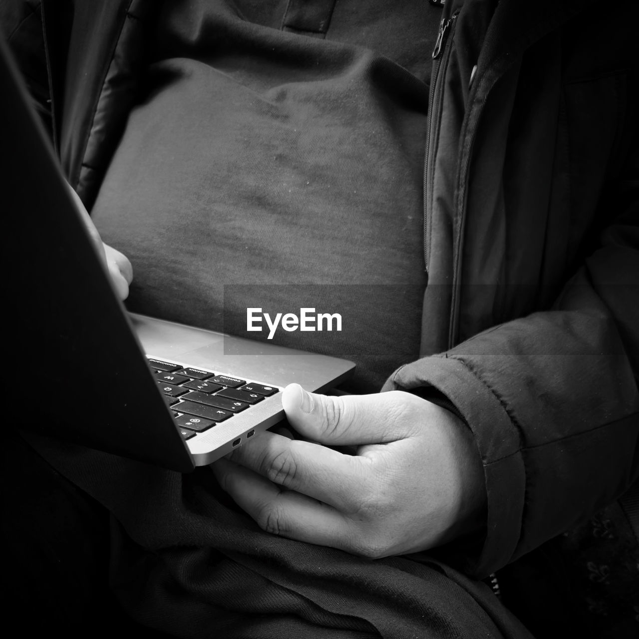 black, black and white, monochrome, monochrome photography, white, one person, midsection, wireless technology, technology, hand, darkness, communication, laptop, adult, person, computer, indoors, sitting, arm, close-up, using laptop, lifestyles, clothing, holding, men