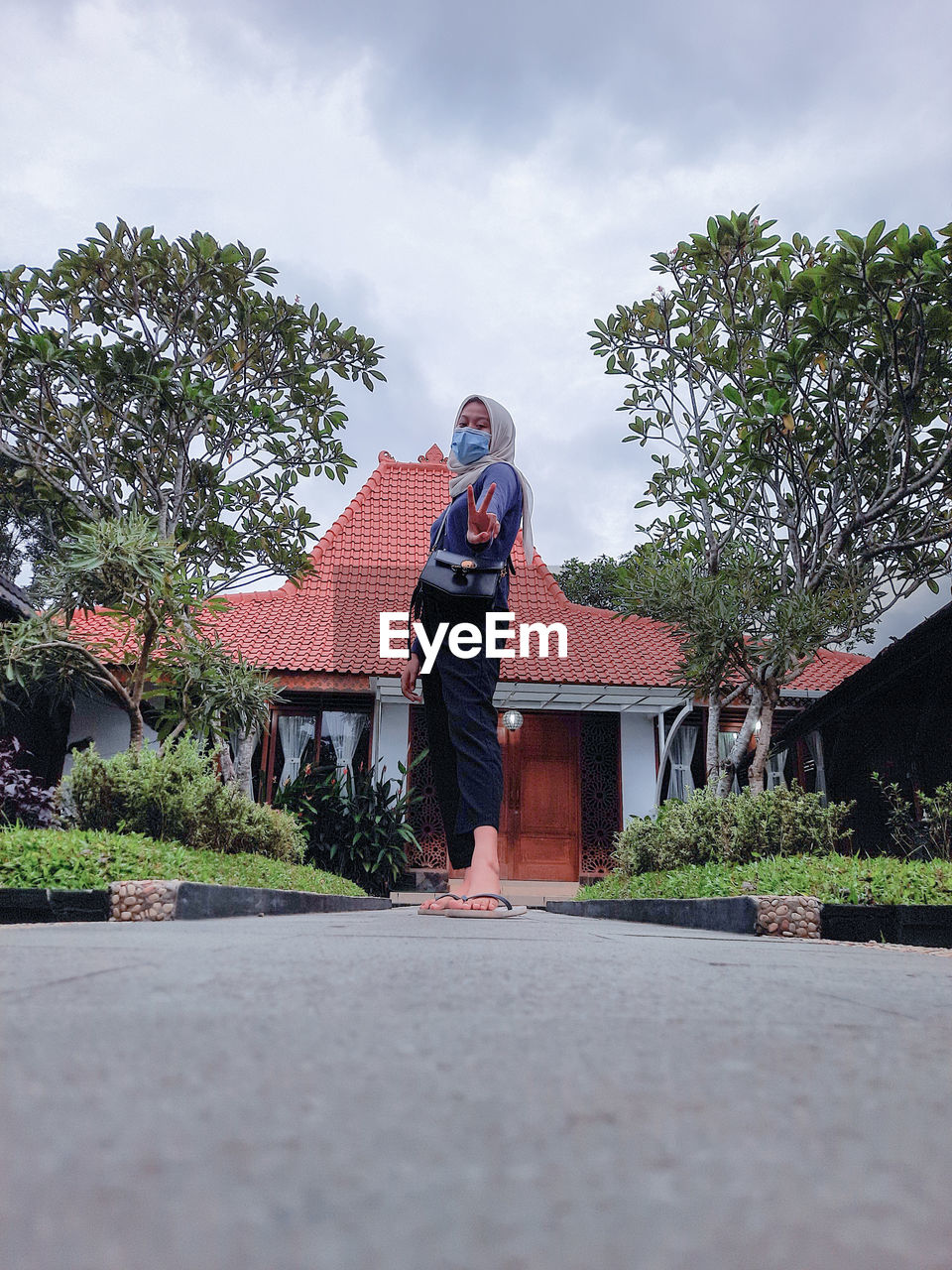 MAN STANDING OUTSIDE HOUSE AGAINST SKY