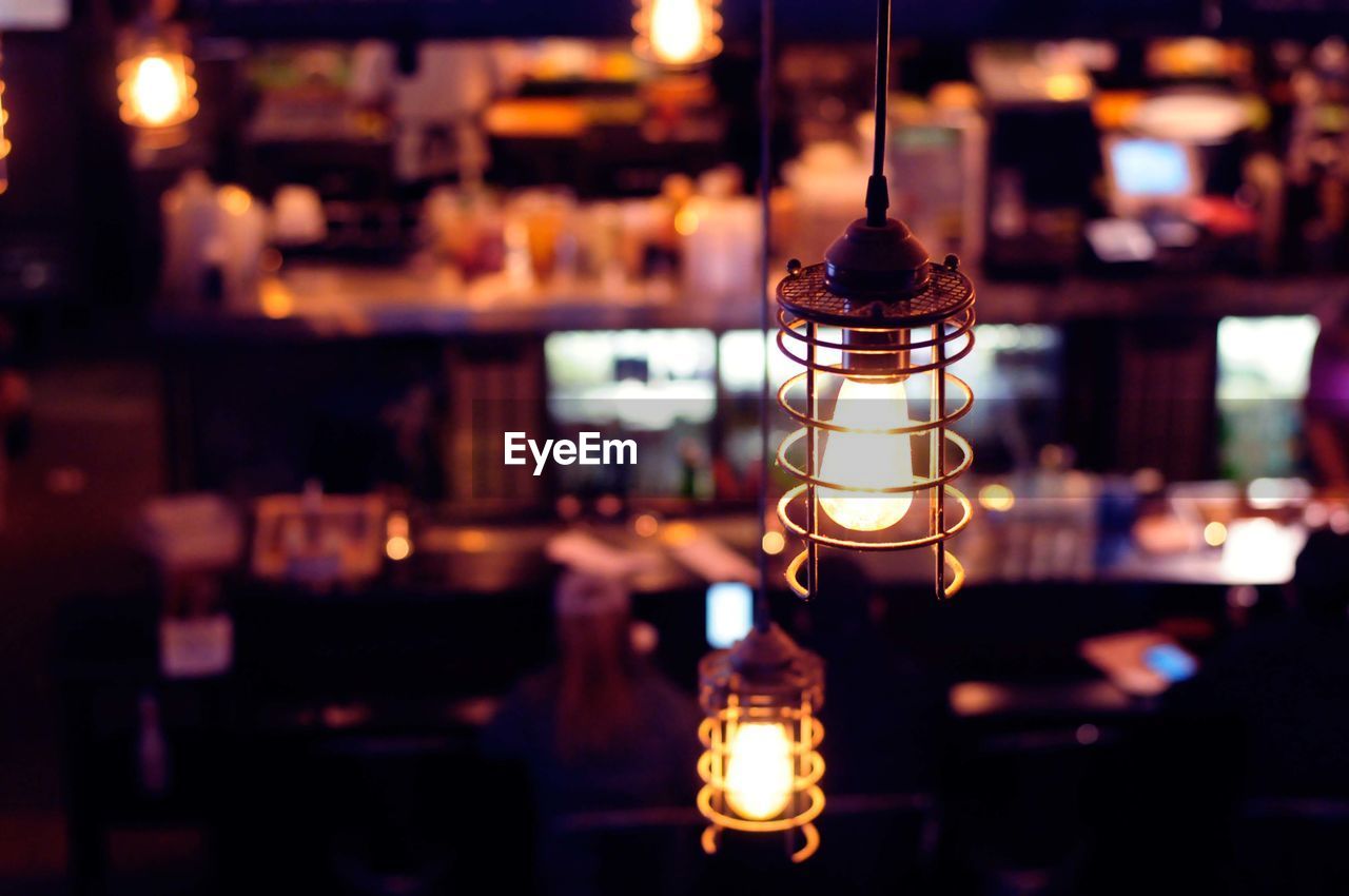 Close-up of illuminated light bulb in restaurant at night