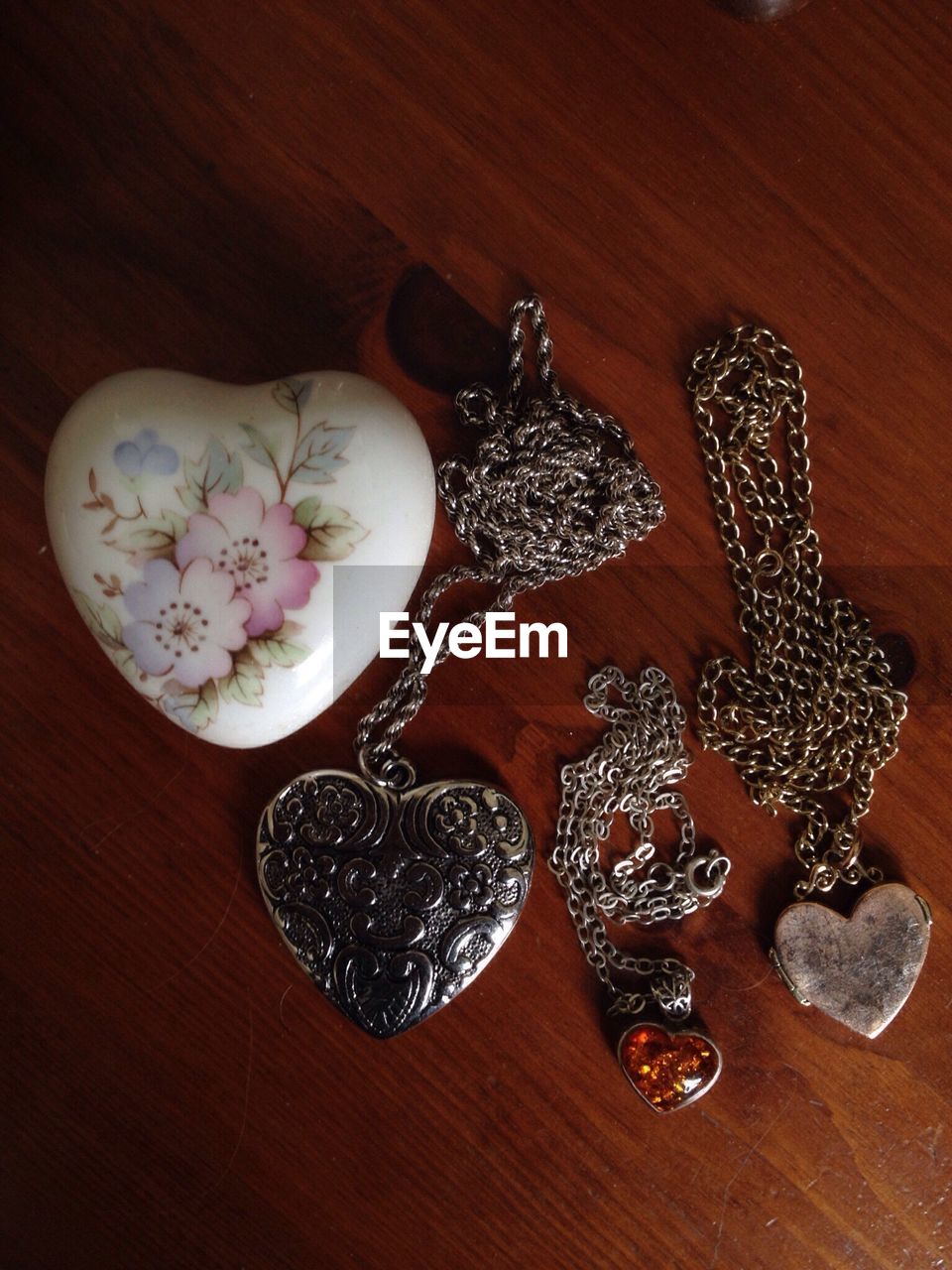 High angle view of heart shape pendant chains and stone on table