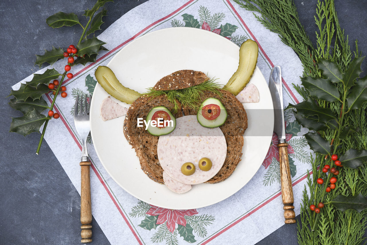 Sandwich in the form of a cheerful bull made of bread,s ausages and vegetables