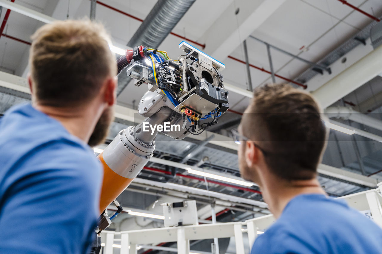 Two technicians examining industrial robot in a factory