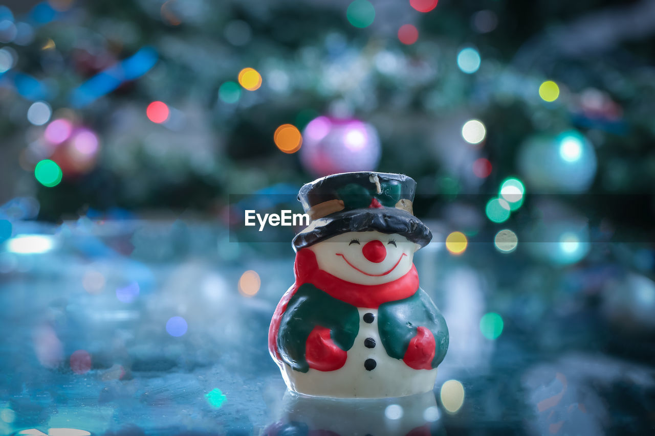 Snowman between candles and christmas tree.