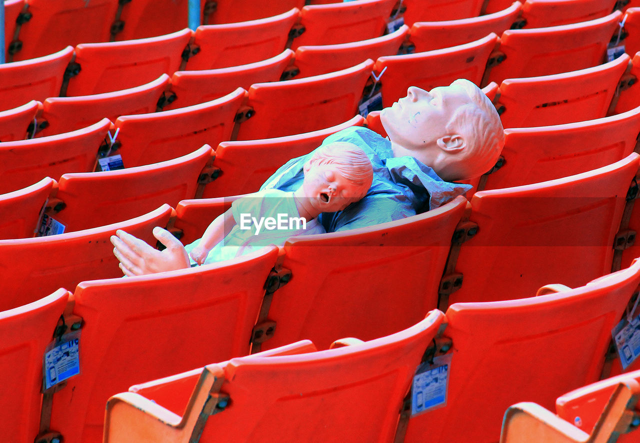 High angle view of mannequins on red chairs at stadium