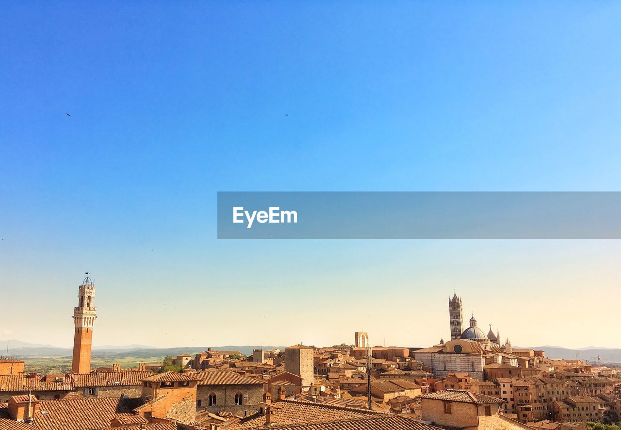 Buildings in city against clear blue sky