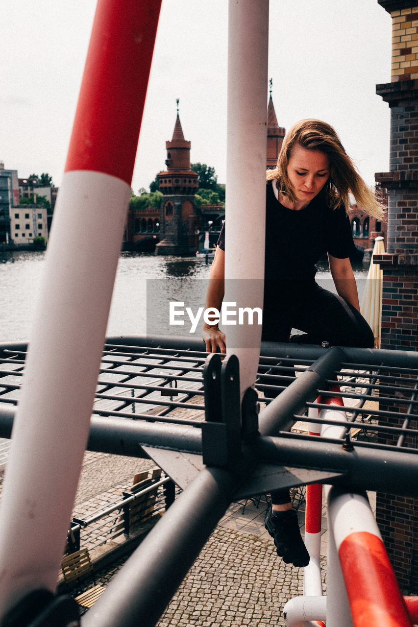 Full length of woman climbing on built structure against sky