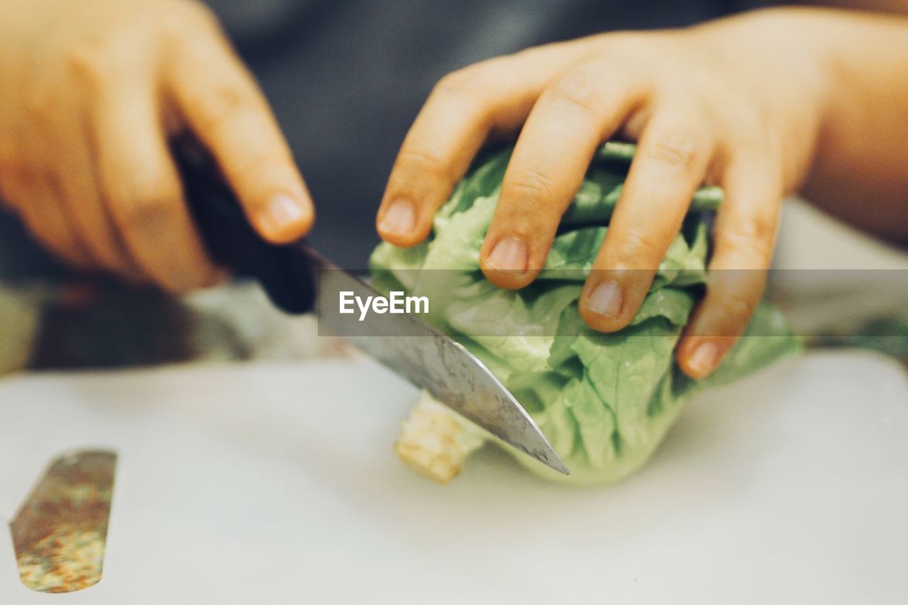 Close-up of person cutting vegetable on table