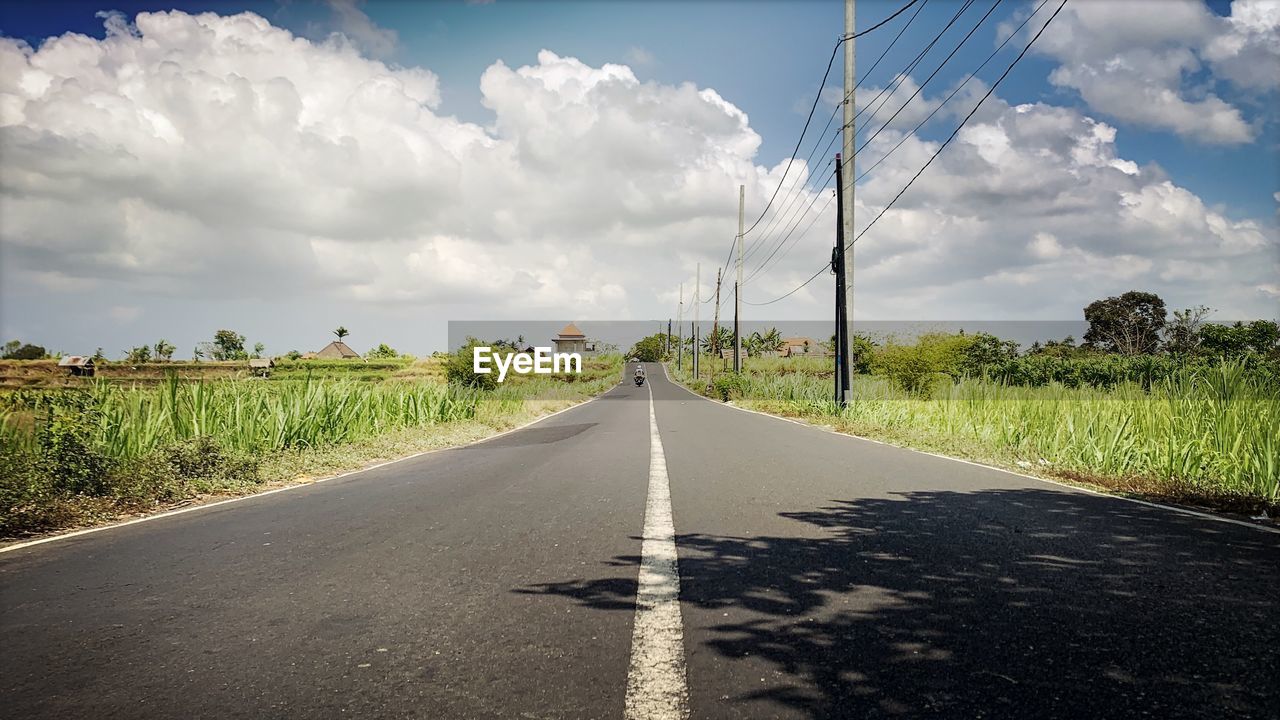 Road amidst field against sky