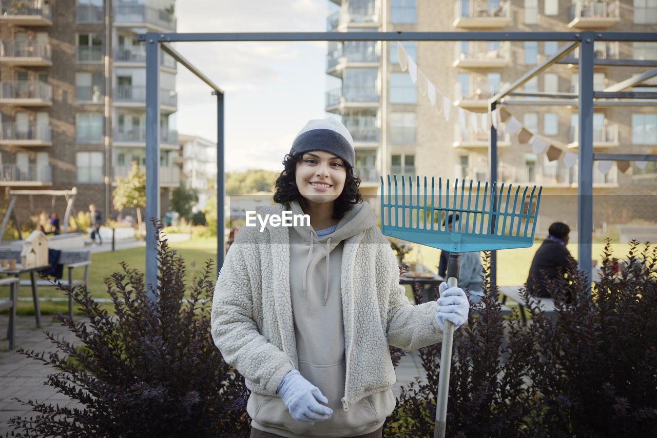 Portrait of smiling teenage girl holding rake