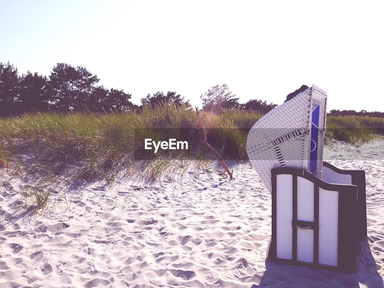 Hooded beach chair on sand against clear sky