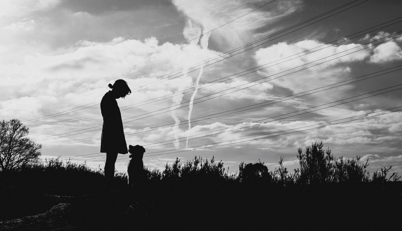 Man standing with dog against sky