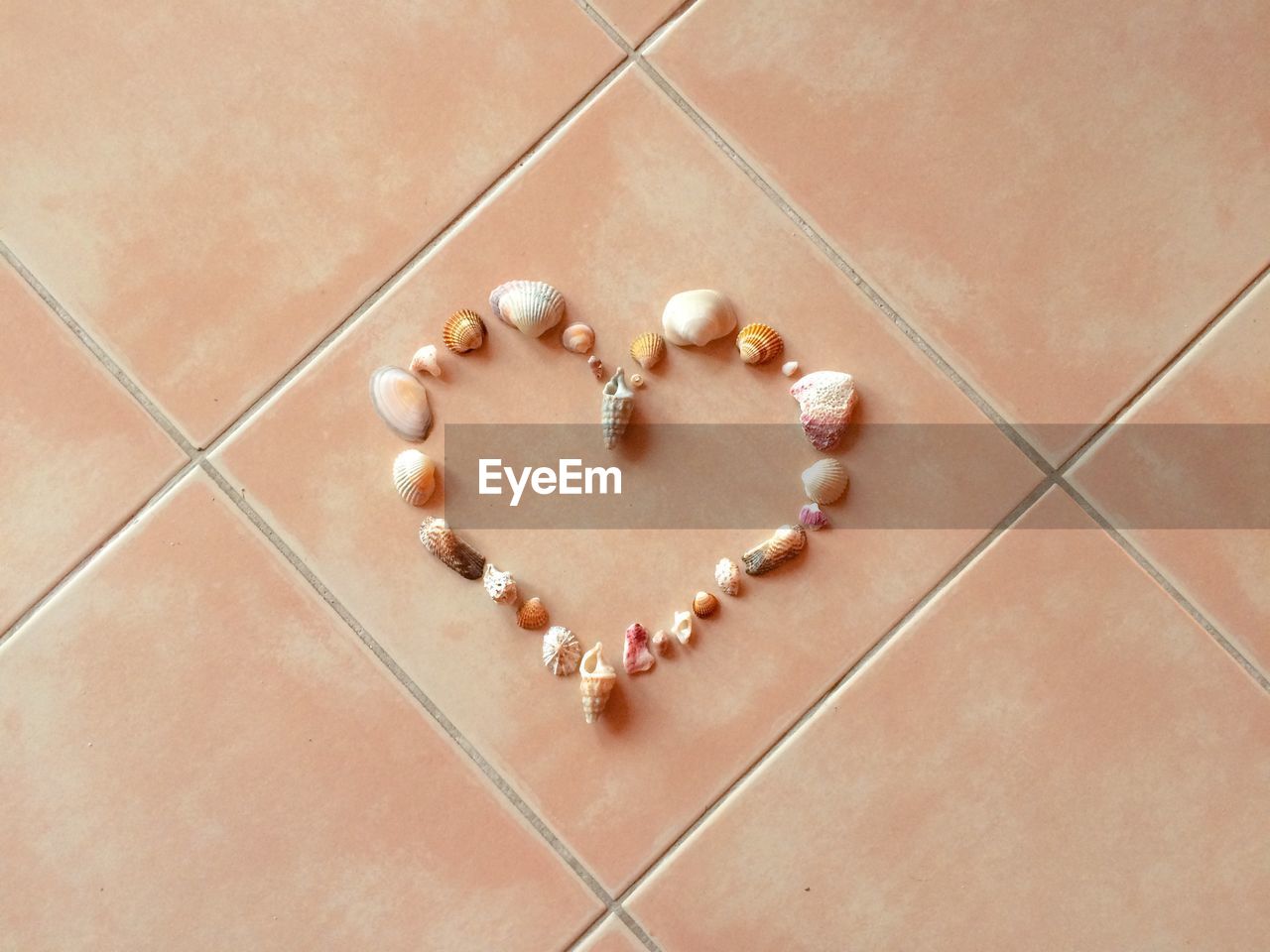 High angle view of heart shape made by seashells on tiled floor