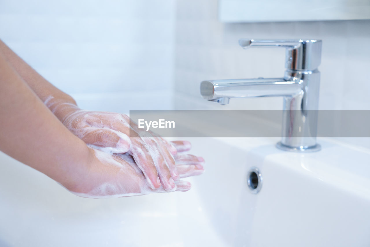 Cropped image of woman cleaning hands by sink in bathroom